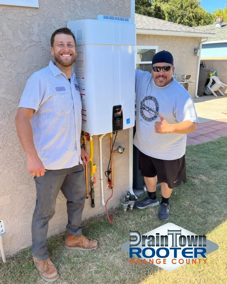 Plumber and a customer giving a thumbs up next to a newly installed tankless water heater
