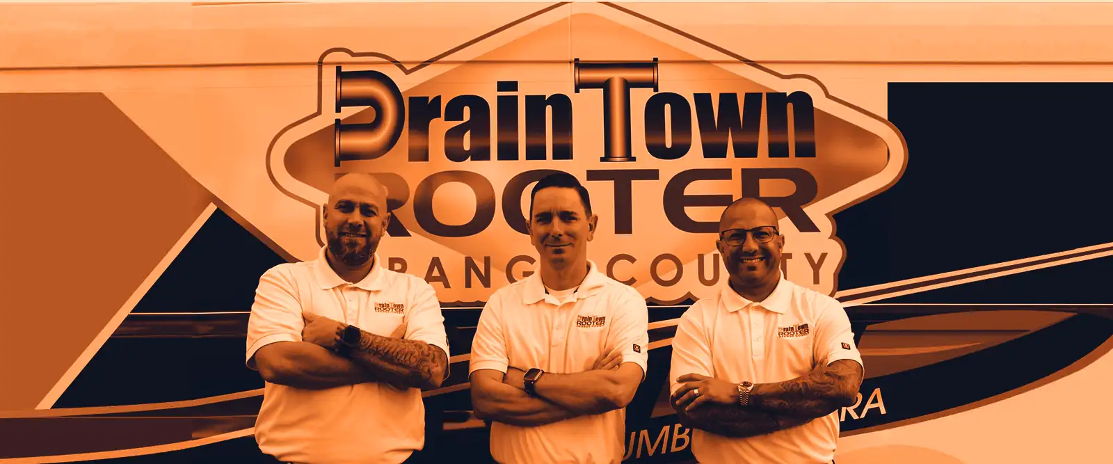 Three Drain Town Rooter plumbers in company shirts in front of a branded service van